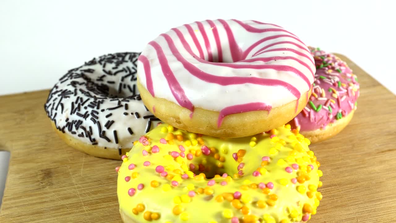 rosquillas giratorias con diferentes rellenos en la mesa. deliciosa rosquilla dulce girando en un plato. rosquilla brillante y colorida macro disparo de primer plano girando sobre un fondo blanco. bucle sin costuras.