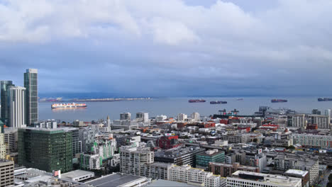panoramic aerial of san francisco city skyline buildings, south beach harbour bay ferry pier and industrial ships in background under stormy sky, ca, usa