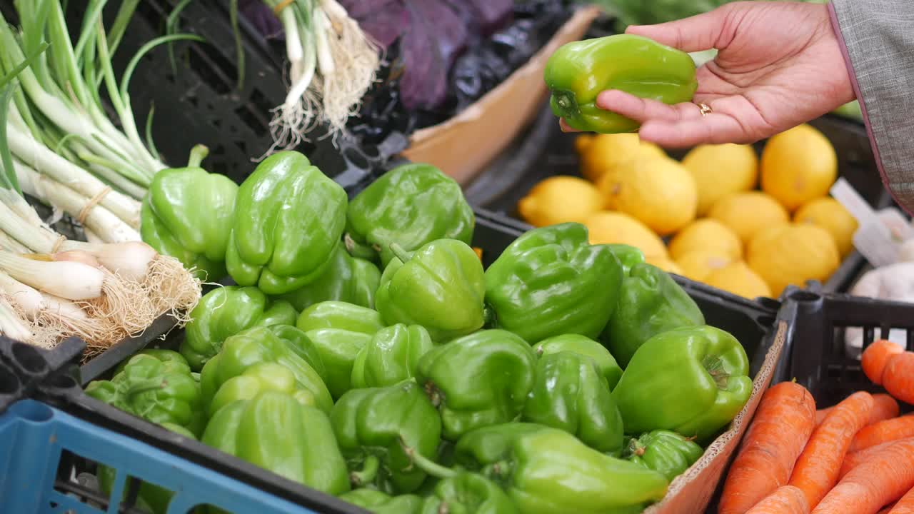 mujer recogiendo pimientos verdes frescos en un mercado