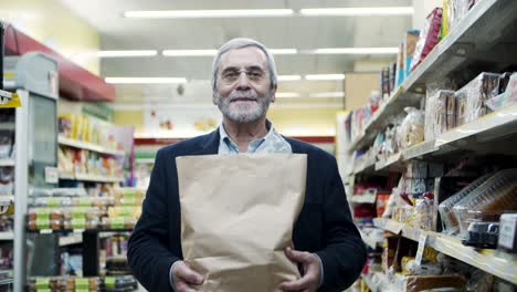 hombre maduro con bolsa de papel en la tienda de comestibles