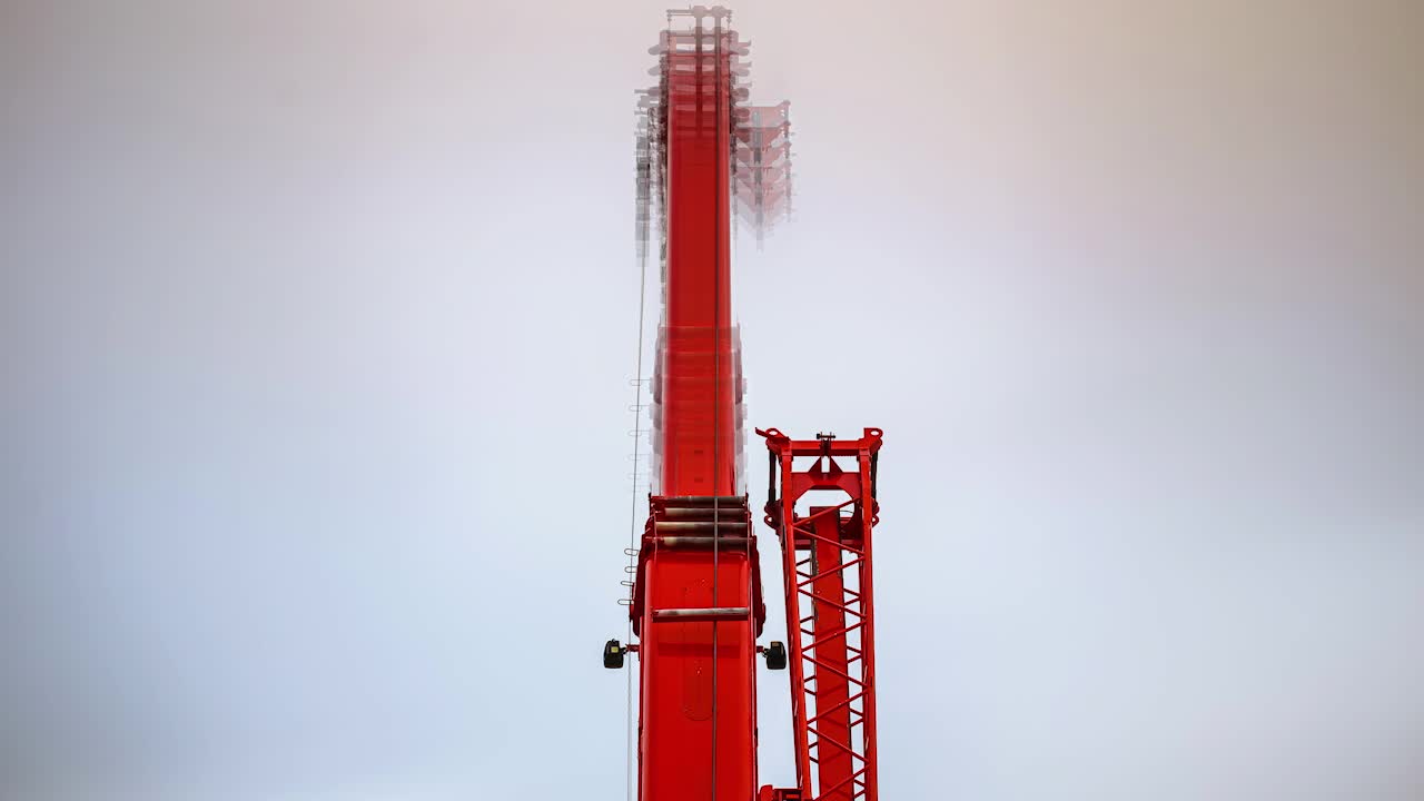 A construction crane extending into the sky on an overcast day - time lapse