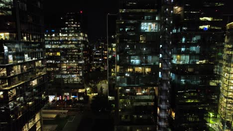 aerial dolly sideways along nueva las condes modern buildings with lights on at night, santiago chile