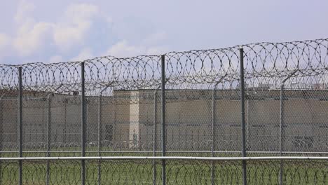 huntsville prison unit exterior of jail in livingston texas outside fence where guards patrol with razor barbed wire fence and building in background establishing shot