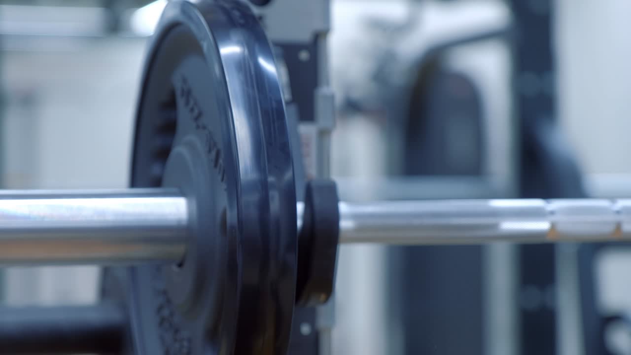 Woman's hands is hanging disc load on a barbell in gym before doing exercise.