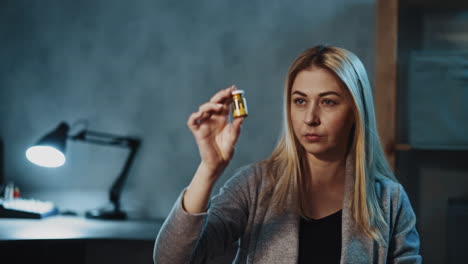 Skeptical-woman-holds-pill-bottle-with-supplement-in-office