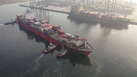 buque de contenedores en puerto con remolcadores