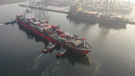 container ship in port with tugboats