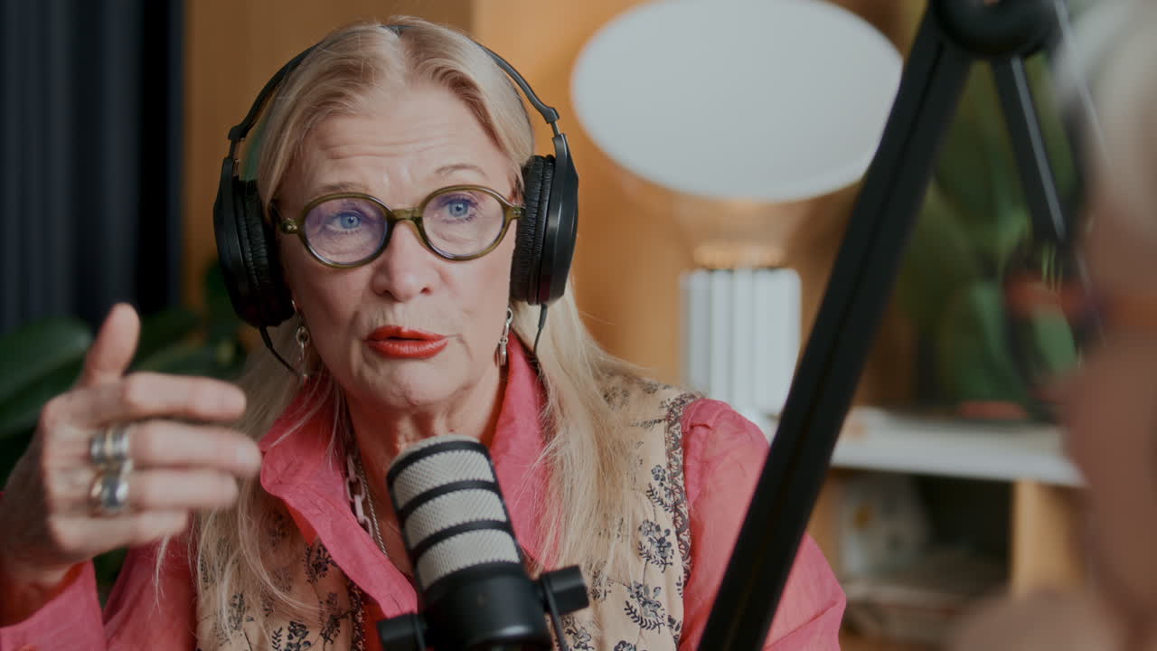 Senior Female Podcaster Speaking into Studio Microphone during Recording Session