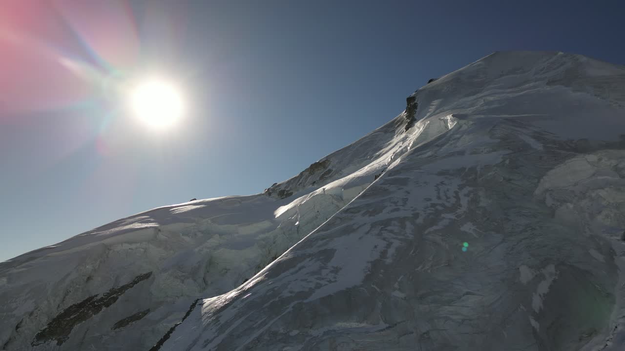 vista aérea de allalin, montaña de los alpes suizos en invierno, sol detrás, cielo azul