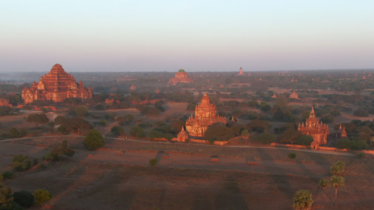 Volo aereo che mostra le pianure di Bagan con il Tempio Dhammayangyi e templi più piccoli sparsi alla luce del sole al tramonto - Myanmar, Asia.