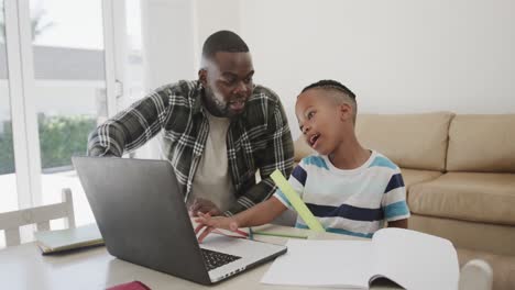 Happy-african-american-father-and-son-using-laptop,-in-slow-motion