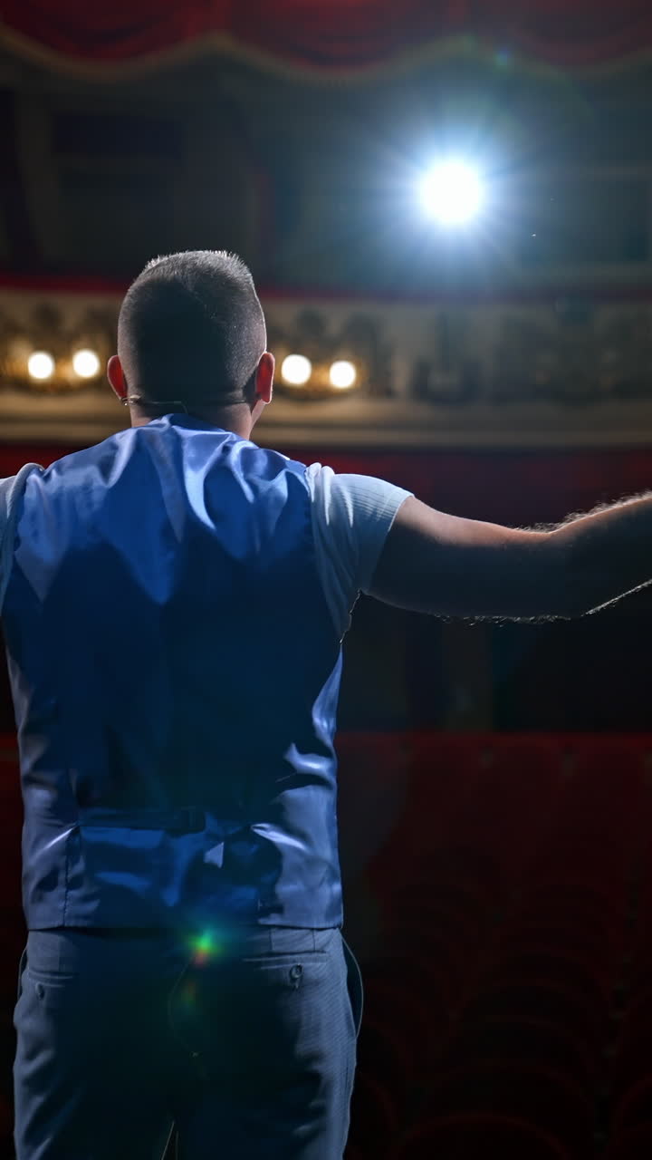 Middle age male entertainer, presenter or actor on stage. Public speaker gives performance in front of empty auditorium. Man in theater. Vertical video