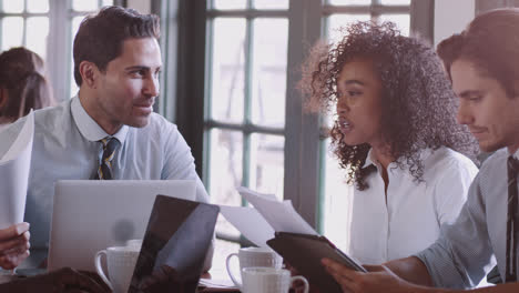 Equipo-De-Negocios-Que-Tiene-Una-Reunión-Informal-Alrededor-De-Una-Mesa-En-La-Cafetería