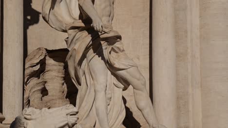 tilt up on the oceanus statue at rome’s trevi fountain, starting from the feet and rising to the upper torso and head, highlighting dynamic baroque sculpting in sunlight.