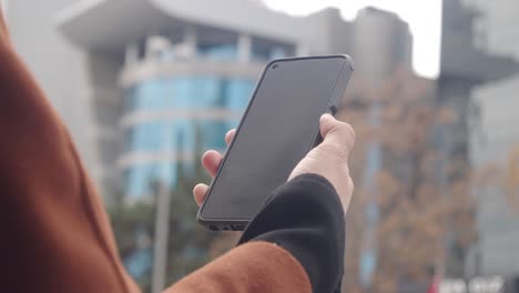 close-up of a person holding a smartphone outdoors