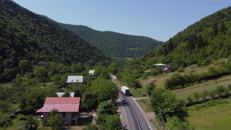 Drohne,-Die-Einem-Großen-Weißen-Lastwagen-Durch-Ein-Tal-Auf-Einer-Georgischen-Straße-Folgt