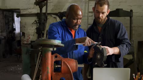 two metalsmiths discussing over metal piece 4k