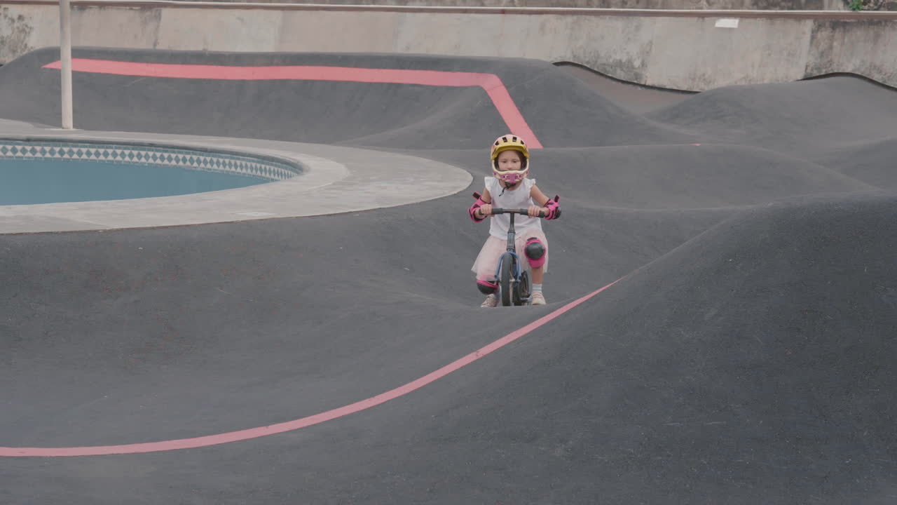 una chica montando una bicicleta de equilibrio en un parque de patinaje