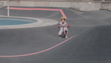 girl riding a balance bike on a skate park