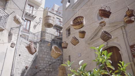 Cesta-De-Paja-Decoración-Colgando-En-La-Calle-Del-Pueblo-Regional-Del-Sur-De-Italia-De-Gangi,-Vistas-De-Los-Montes-Madonie-En-La-Provincia-De-Palermo-Sicilia-Italia