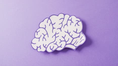 video of purple and white paper brain on purple background with copy space