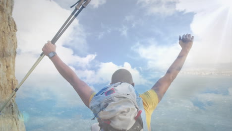 animation of sky with clouds over caucasian man with arms outstretched hiking