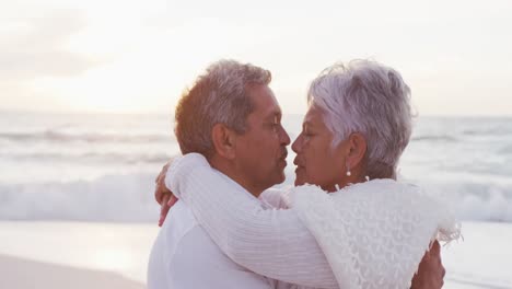 happy hispanic just married senior couple kissing on beach at sunset