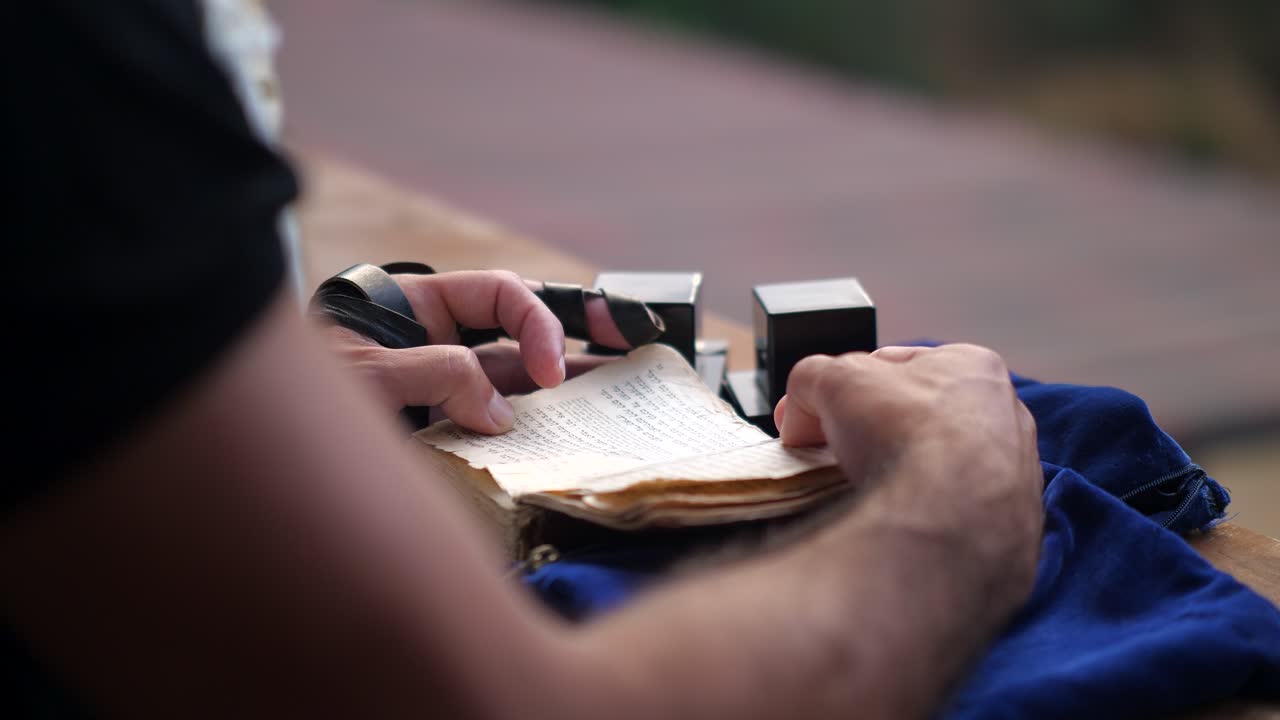 Close up of man praying with tefillin and Hebrew prayer book