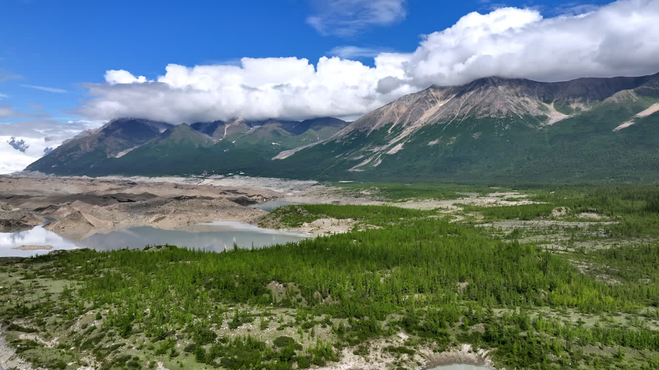 Stunning Alaskan wilderness. Explore the stunning beauty of Alaska, featuring majestic mountains and a serene river surrounded by lush greenery