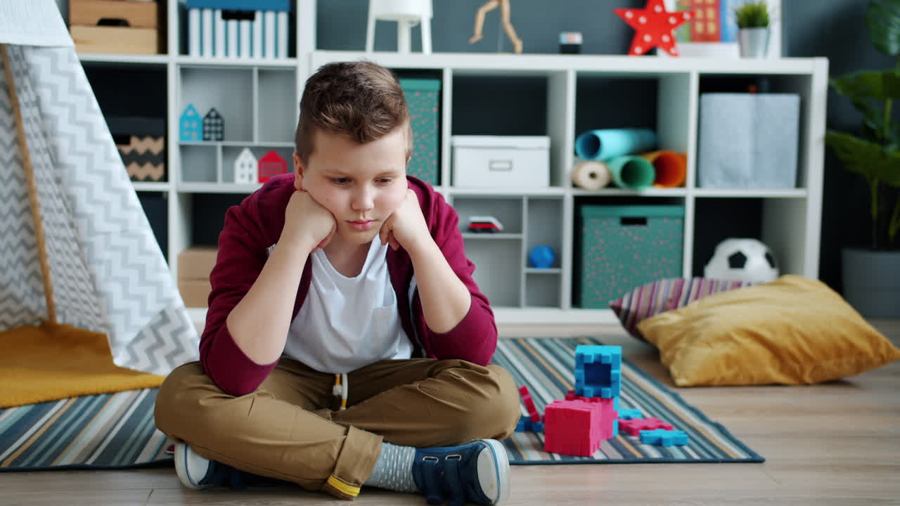 Un bambino triste seduto per terra in una sala giochi