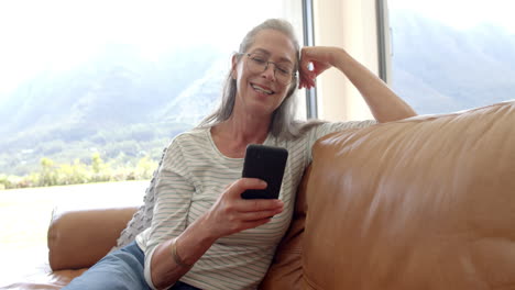 Mature-Caucasian-woman-sitting,-holding-smartphone,-smiling