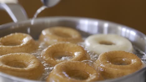 close-up of flipping perfectly browned homemade donuts in hot oil