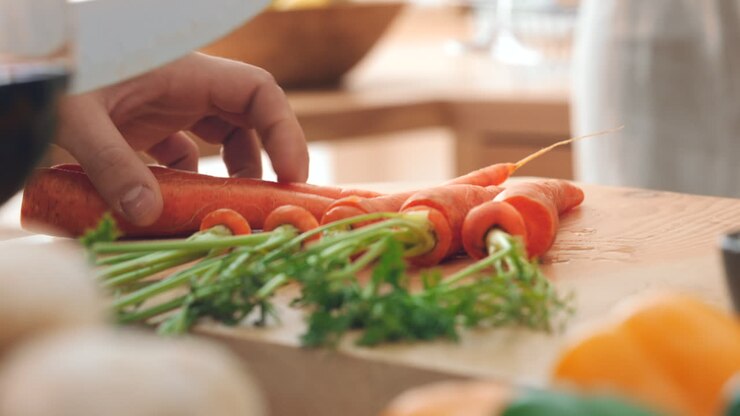 Hands, chef or person cutting carrots on board