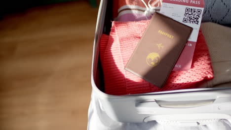 un pasaporte y una tarjeta de embarque descansan encima de la ropa en una maleta abierta