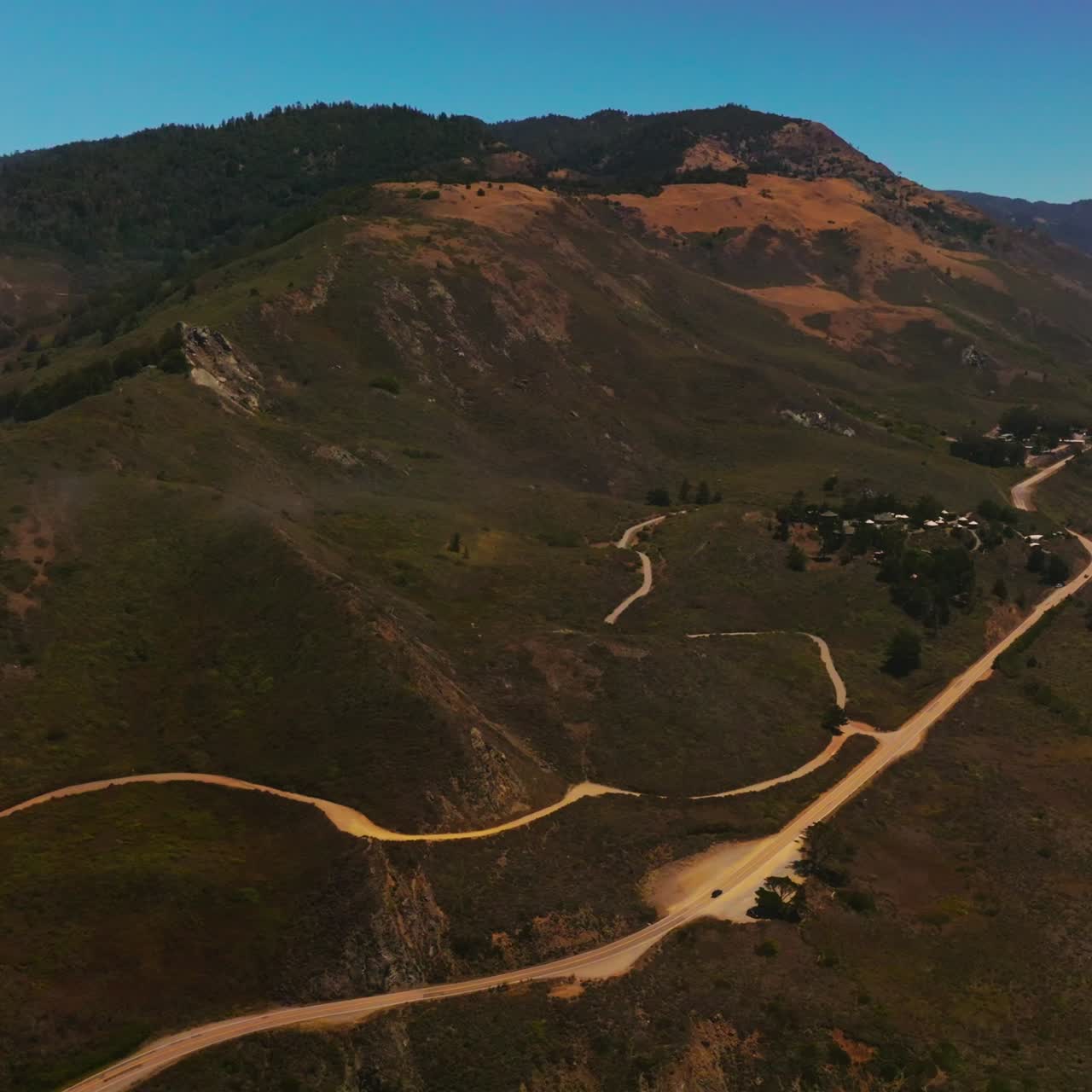 Motorways and footpaths on the sloping mountain. California rocky shore on sunny daytime from aerial view