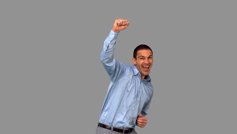 cheerful businessman raising his fist on grey screen