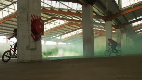 jinetes de bmx en un almacén vacío usando una granada de humo