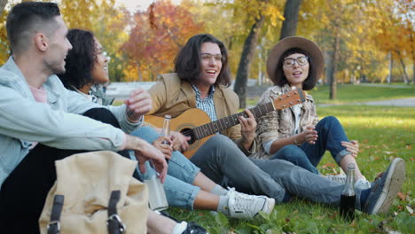 friends playing guitar in autumn park