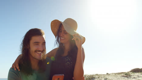 Couple-using-mobile-phone-on-the-beach-4k