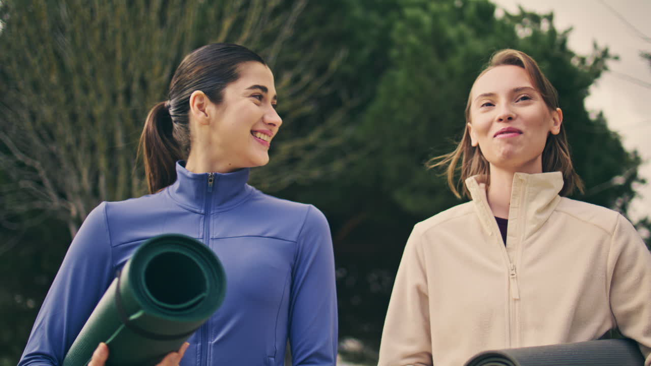 Smiling sport women speaking together walking at park. Excited ladies crossing