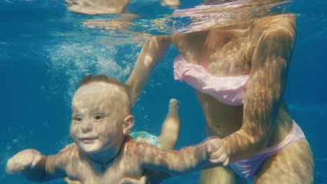 el bebé se zambulle en la piscina video submarino mamá lo apoya cuidadosamente