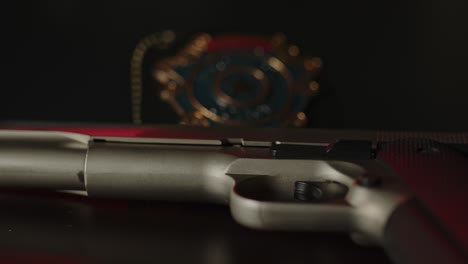gun lying on a dark surface with an out of focus police badge in the background