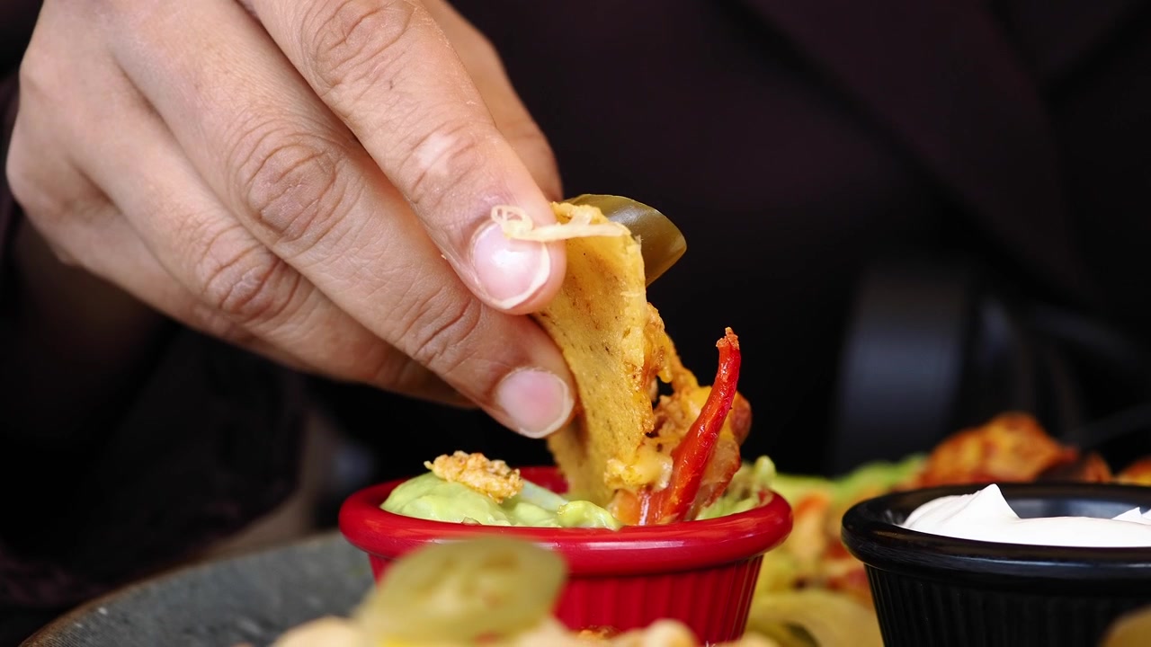 Persona che intinge un nacho nel guacamole