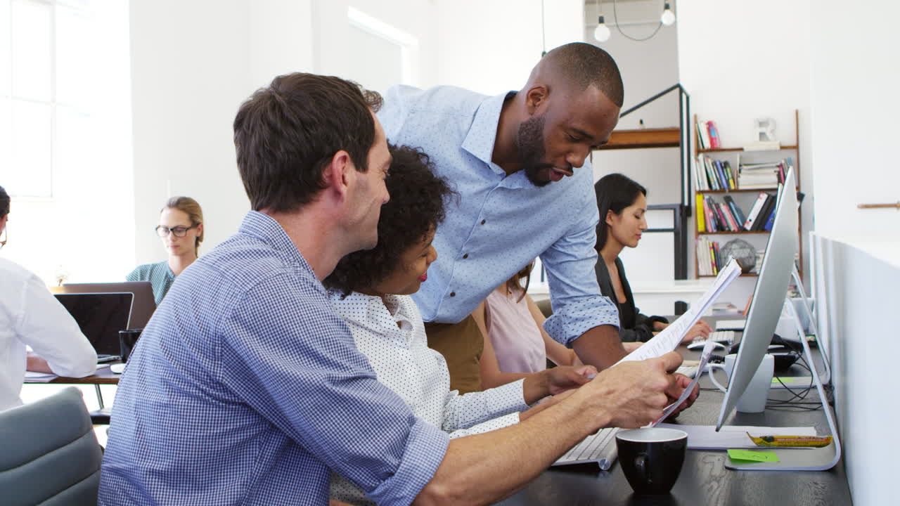 Two men and a woman working together in open plan office