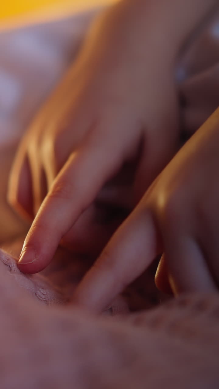 Little girl touches pink woolen covering by small fingers before going to sleep on bed in semidark bedroom in evening extreme close view slow motion