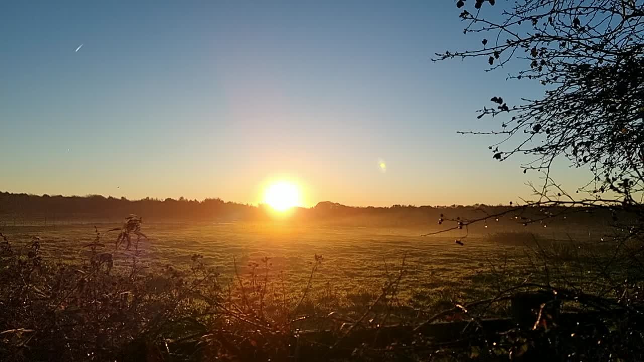 Early morning golden glowing sunrise over misty cold autumn farmland meadow