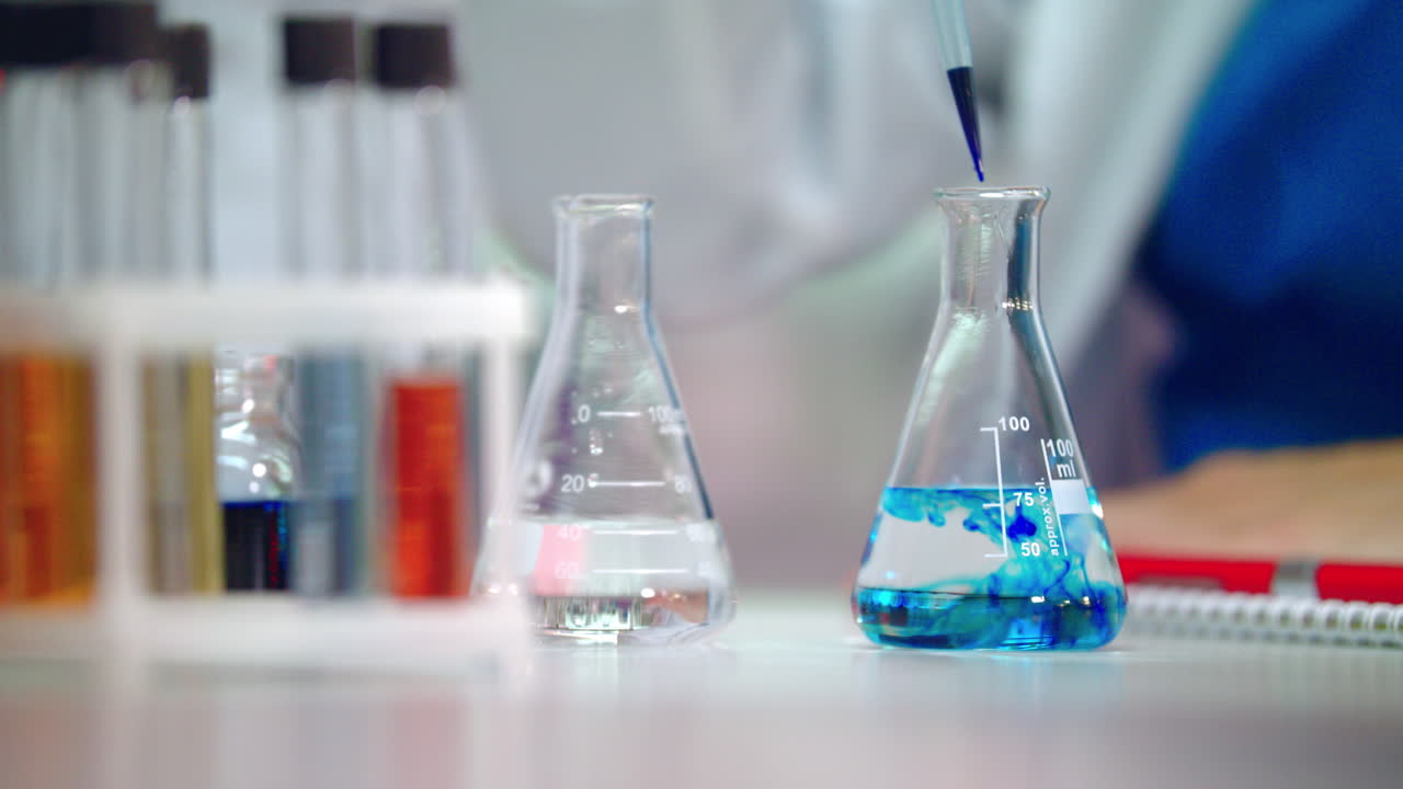 goteo de líquido químico en un frasco de vidrio. reacción química en un frasco de laboratorio