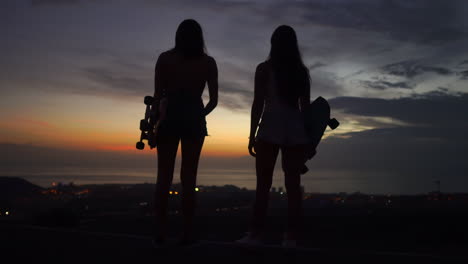 En-La-Cima-De-La-Montaña,-Los-Amigos-Dejan-De-Andar-En-Patineta-Para-Maravillarse-Con-El-Pintoresco-Cielo-Del-Atardecer.