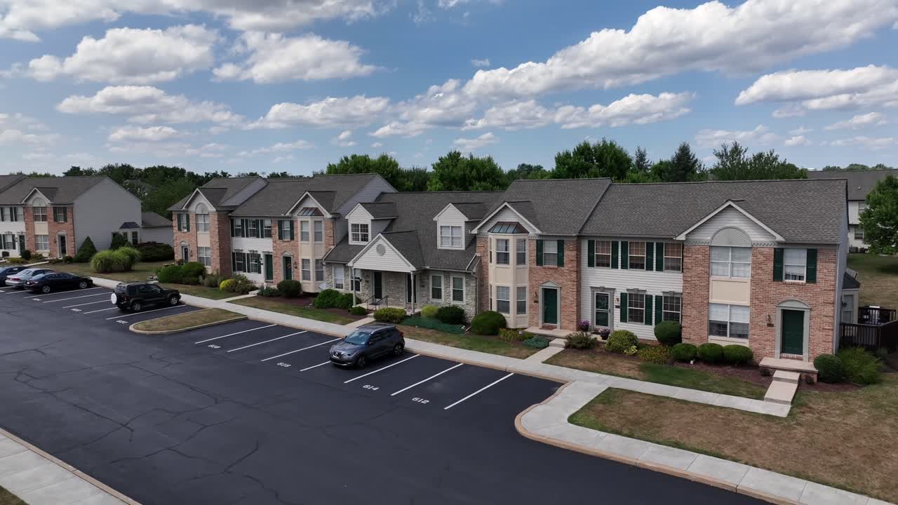 Row of houses with parking cars during sunny day with clouds at sky. American homes in suburb neighborhood. Aerial orbit shot.