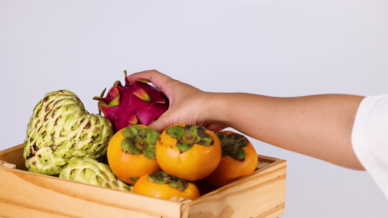 seleccionando a mano la fruta del dragón de una canasta de frutas